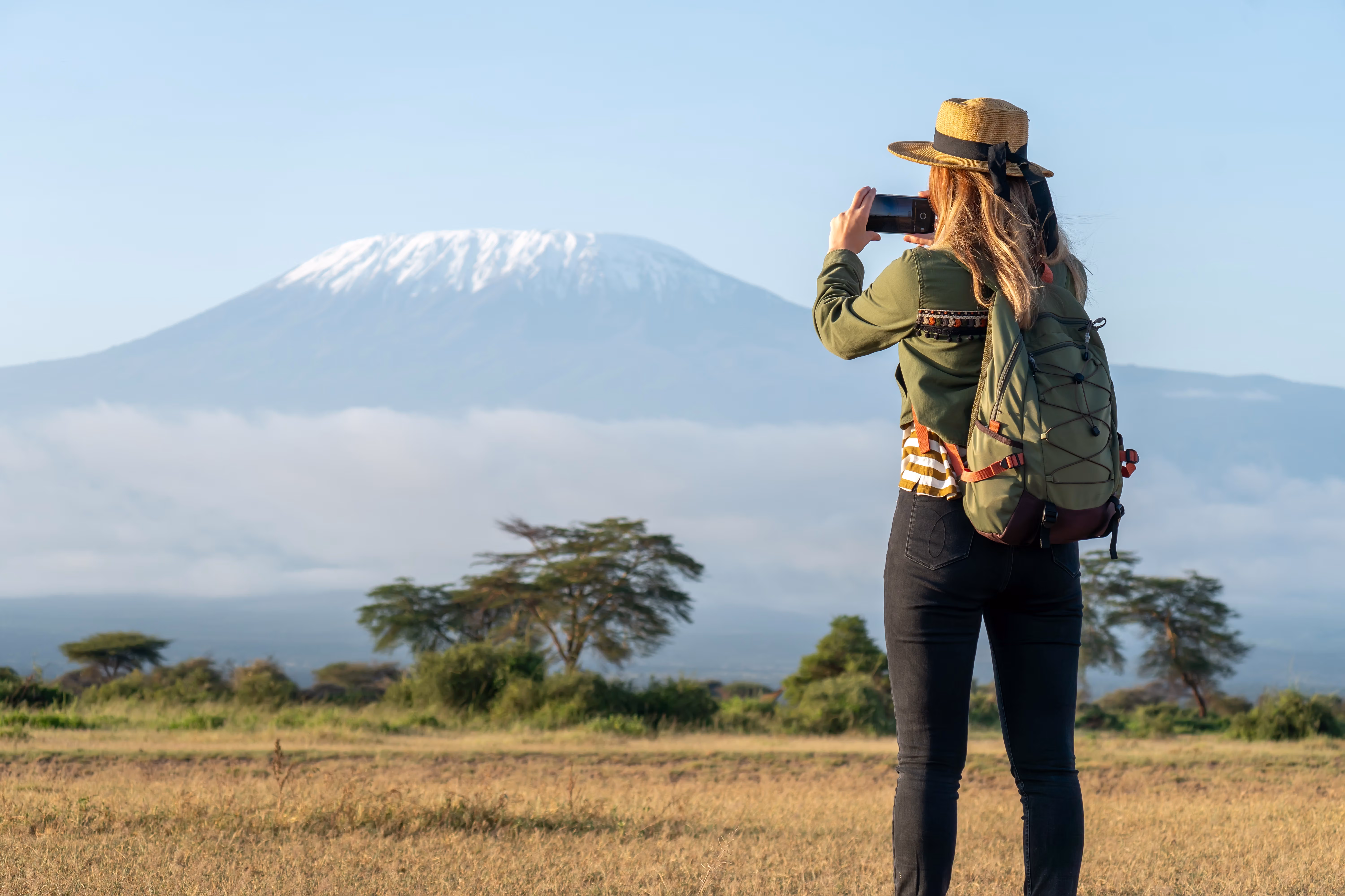 A traveller photographing Kilimanjaro across the plain at first light